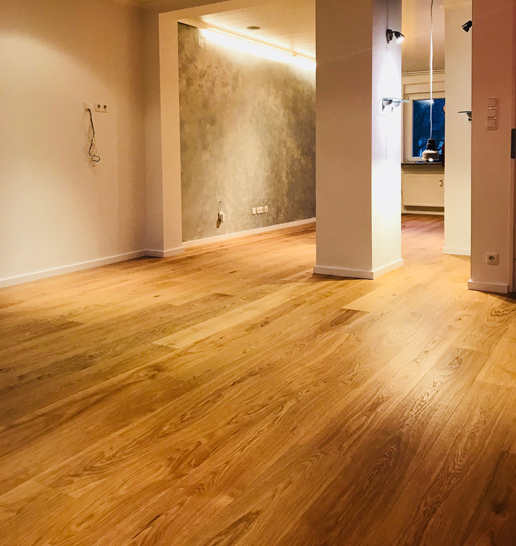 Großer leerer Raum mit Holzparkett und Säulen